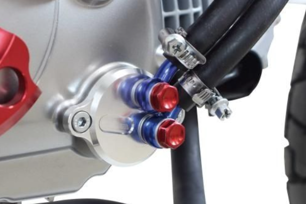 Close-up of a motorcycle's fuel system with red and blue fuel caps.