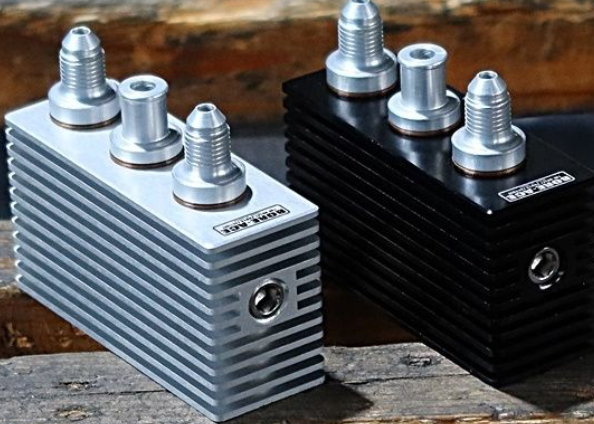 Two metal blocks with threaded connectors on a wooden surface