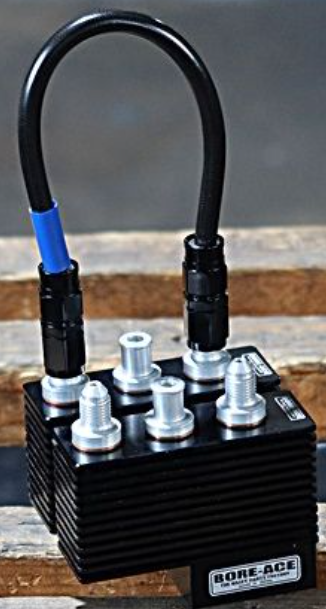 Black metal block with cylindrical components and hoses on a wooden surface