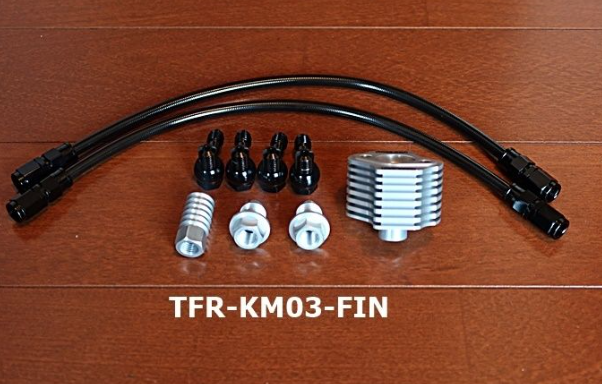 Set of automotive parts including hoses, connectors, and metal components on a wooden surface with 'TFR-KM03-FIN' label.