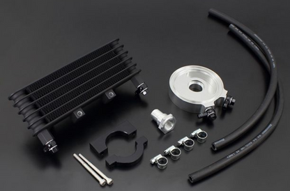 Collection of automotive parts including a black radiator, silver pulley, and black hoses on a dark background.