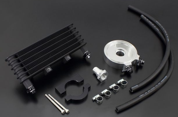 Collection of automotive parts including a black radiator, silver pulley, and black hoses on a dark background.