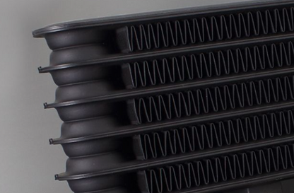 Stack of black plastic trays with ribbed design on a gray background