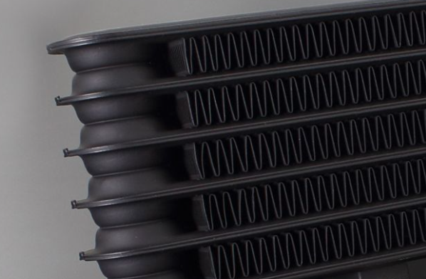 Stack of black plastic trays with ribbed design on a gray background