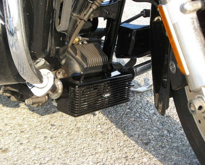 Close-up of a motorcycle's foot peg and engine area on a textured surface.