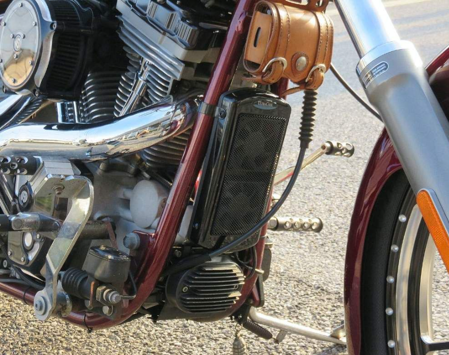 Close-up of a motorcycle engine and exhaust system on a road.