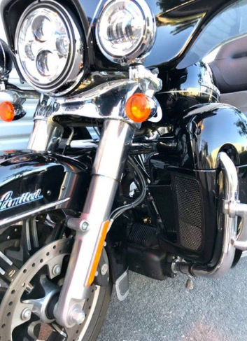 Close-up of a motorcycle's front headlight and grille with 'Harley-Davidson' branding.