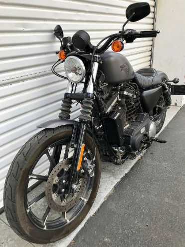 Black motorcycle parked against a white wall