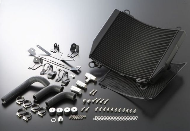 Car cooling system parts including a black radiator and various metal components on a reflective surface.