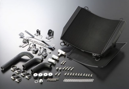 Car cooling system parts including a black radiator and various metal components on a reflective surface.