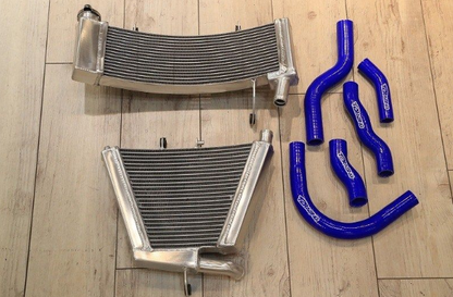 Two metal radiators and three blue silicone hose pieces on a wooden floor.