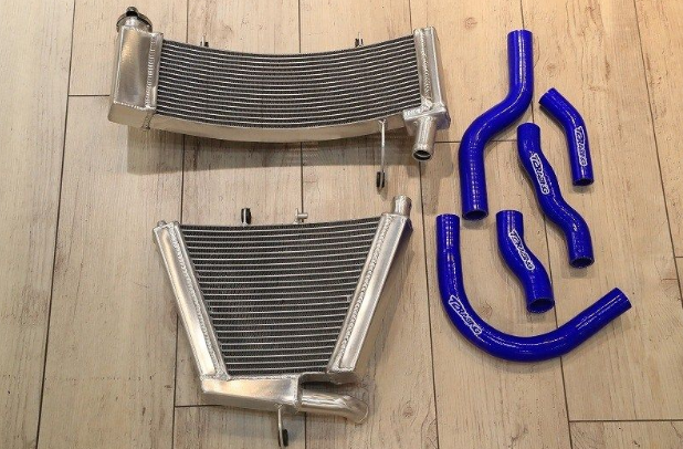 Two metal radiators and three blue silicone hose pieces on a wooden floor.