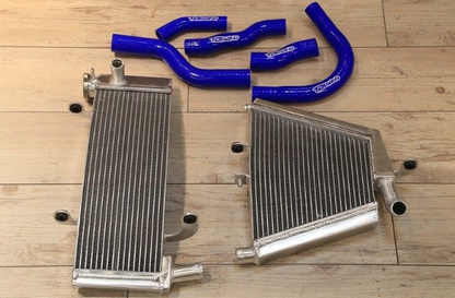Two metal radiators and blue silicone hoses on a wooden surface