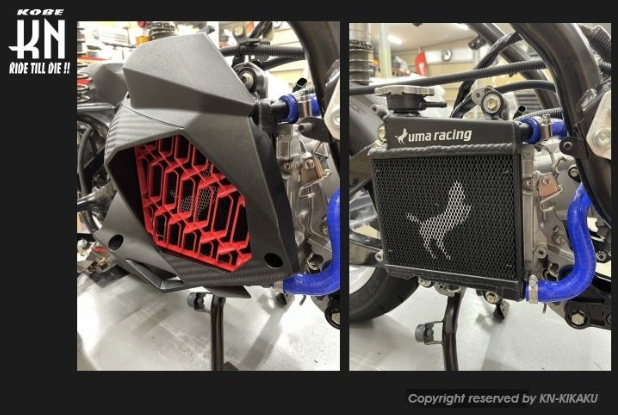 Close-up of a motorcycle radiator with 'Kuma Racing' branding and 'Kobe' logo.