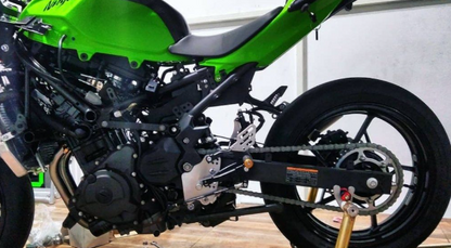 Close-up of a green motorcycle with visible branding on a wooden floor.