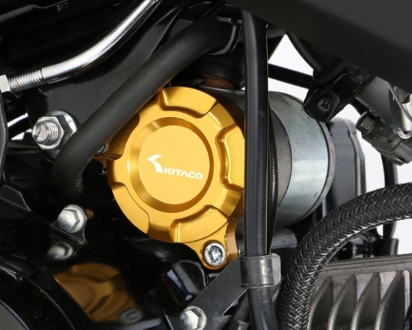 Close-up of a motorcycle's gold clutch cover with Kitaro branding.