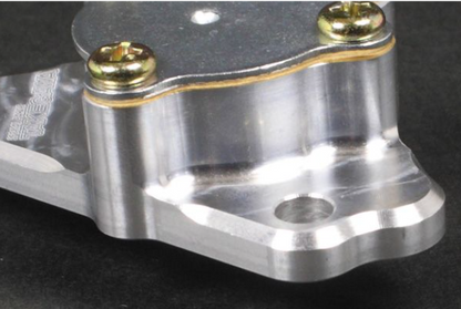 Metal mechanical component with gold screws on a dark background