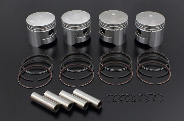 Set of piston rings and pins on a dark background
