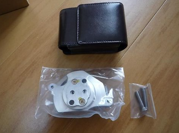Mechanical component in a clear plastic bag with a black leather case on a wooden surface