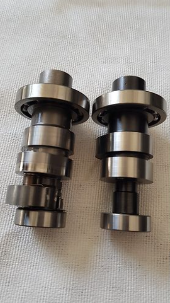 Two metal camshafts on a light fabric background