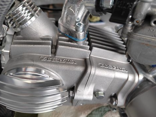 Close-up of a metallic engine component with 'Takemoto' branding.