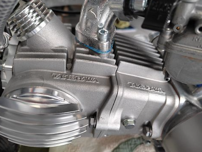 Close-up of a metallic engine component with 'Takemoto' branding.