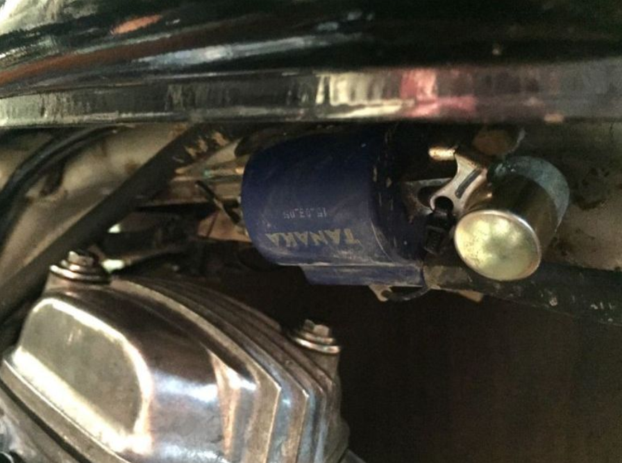 Close-up of a motorcycle headlight with a blue tag labeled 'TANKA'.