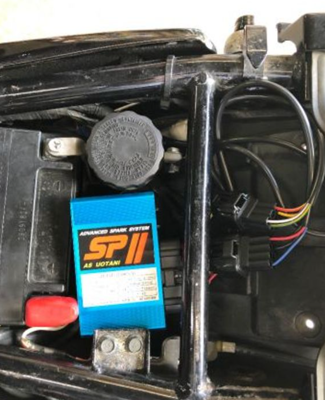 Car battery with an advanced spark system installed in a vehicle's engine bay.
