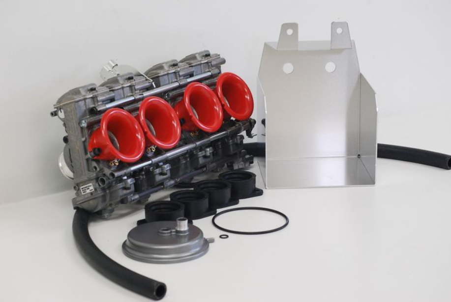 Car engine block with red valve covers and metal components on a white background