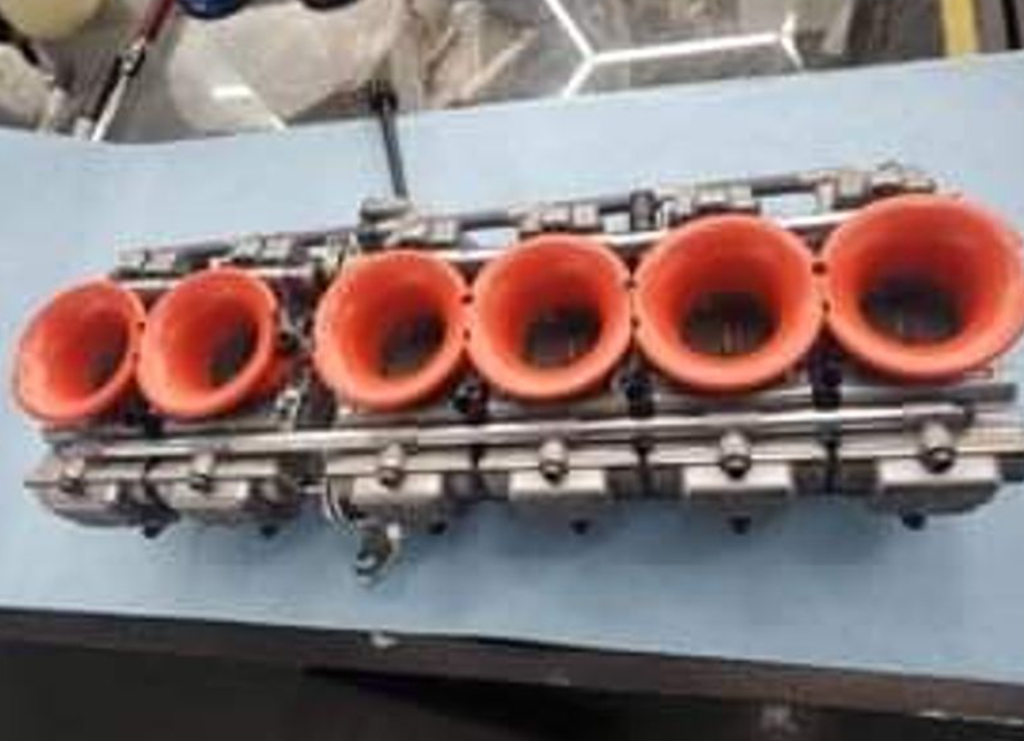 Engine cylinder head with red valve covers on a blue surface