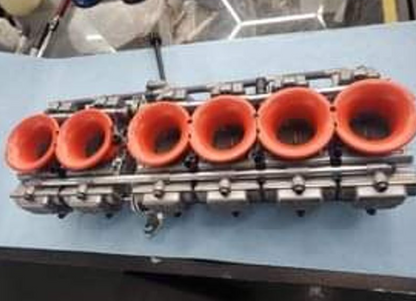 Engine cylinder head with red valve covers on a blue surface