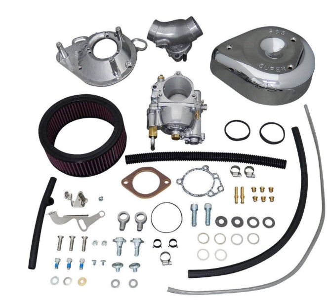 Collection of automotive parts including a carburetor, air filter, and various metal components on a white background.