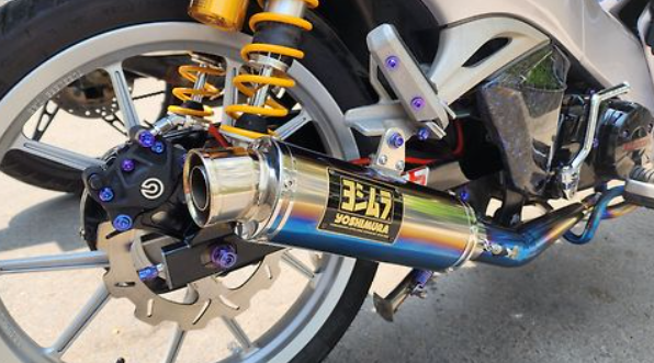 Close-up of a motorcycle exhaust with Yoshimura branding on a road.