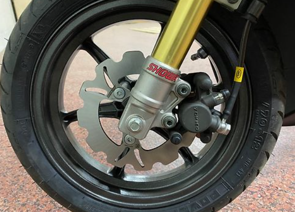 Close-up of a motorcycle wheel with Showa suspension on a blurred background