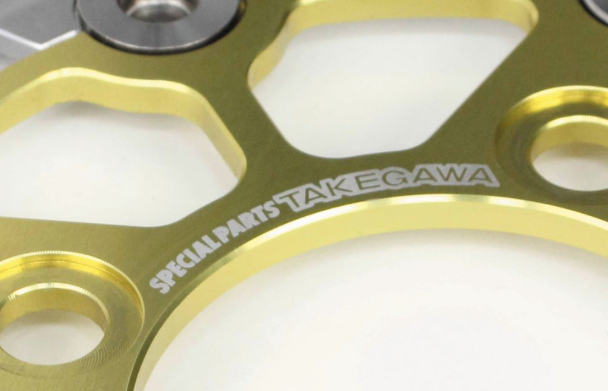 Gold metal gear with 'Special Parts Takegawa' branding on a white background