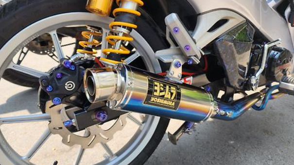 Close-up of a motorcycle exhaust with Yoshimura branding on a concrete surface.