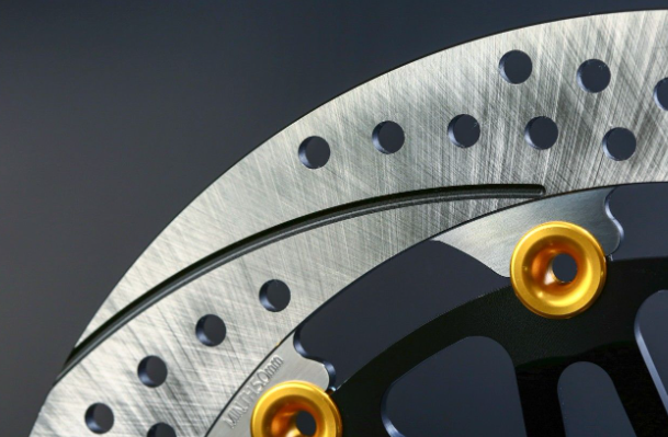 Close-up of a brake disc with gold bolts on a dark background