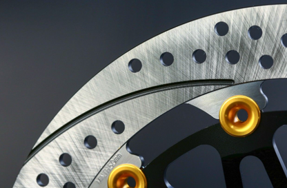 Close-up of a brake disc with gold bolts on a dark background