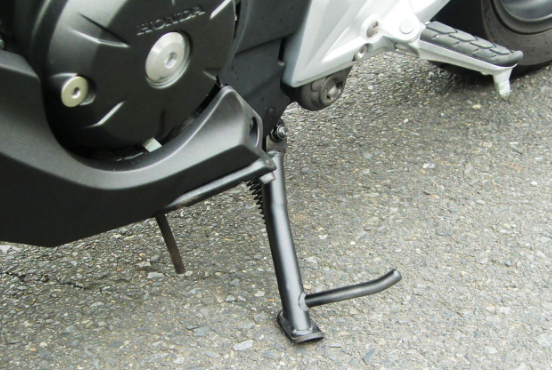 Motorcycle kickstand on a road with a blurred background