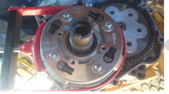 Mechanical component with gears and red housing on a reflective surface