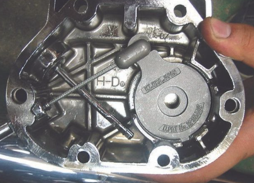 Close-up of a motorcycle engine part with 'H-D' branding, held by a hand.